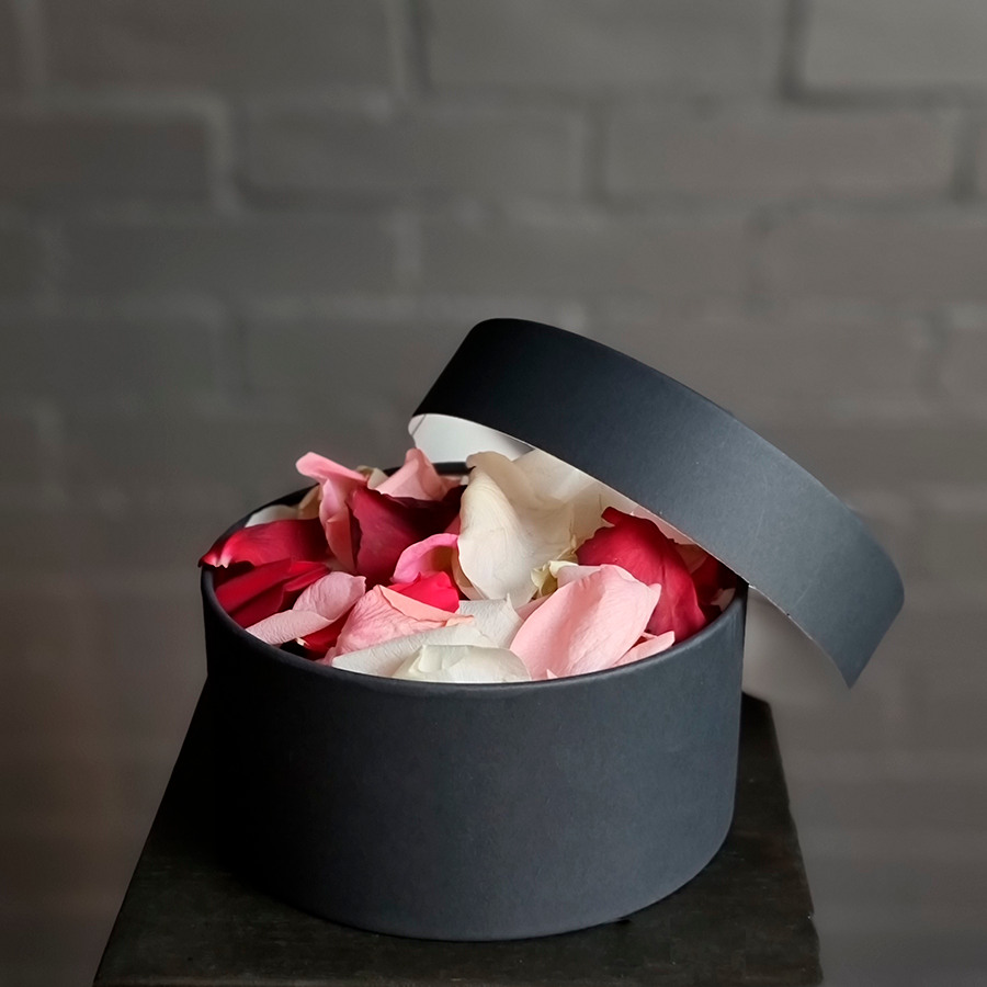 Лепестки роз в круглой коробке, черного цвета.