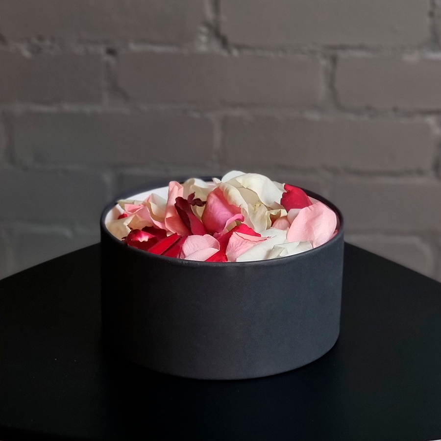 Лепестки роз в круглой коробке, черного цвета.