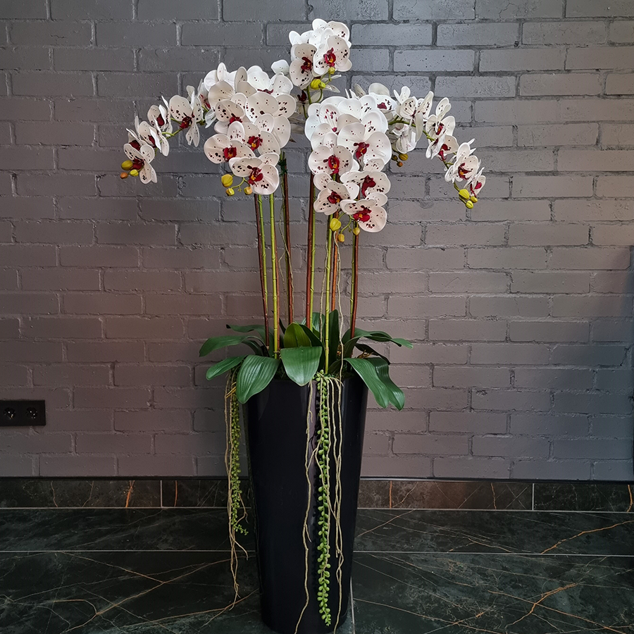 7 искусственных фаленопсисов в высоком, напольном кашпо.