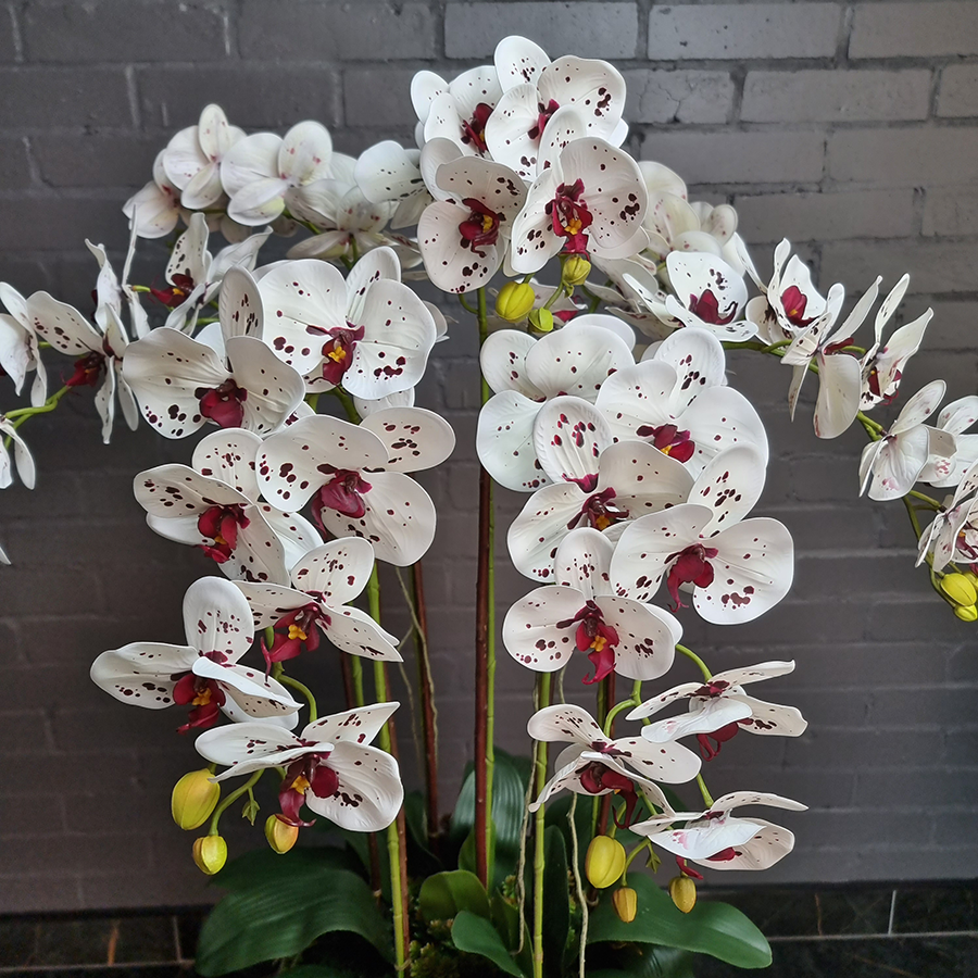 7 искусственных фаленопсисов в высоком, напольном кашпо.